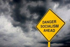 A Caution Sign In Front Of Storm Clouds Warning Of "socialism Ahead."